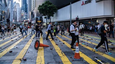 People cross a road after protesters threw bricks onto it in order to stop traffic passing in the Causeway Bay area of Hong Kong on November 11, 2019. (AFP)