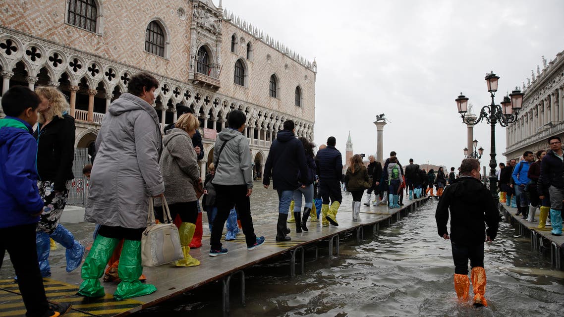 Tourists walk on wooden platforms in flooded St. Mark's Square in Venice, Italy, Thursday, Nov. 1, 2018 as rainstorms and strong winds have been battering the country. (AP)
