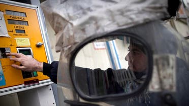 An Iranian man inserts his fuel smart card in the machine to fill his motorcycle at a petrol station in central Tehran. (File photo: AFP)