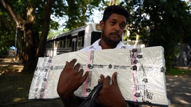 An electoral official waits to board a bus after collecting ballot papers and boxes from a distribution centre for their respective polling stations on the eve of the presidential election, in Colombo. (AFP)