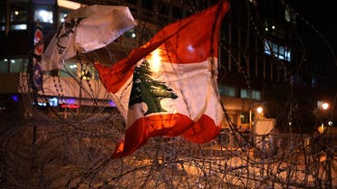 The Lebanese flag hangs on barbed wire blocking a road leading to the parliament building in downtown Beirut on November 18, 2019. (AFP)