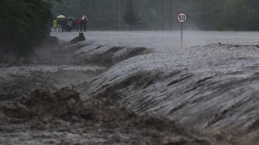 People watch as flash floods rage past a part of the main highway to Kenya's border town with Tanzania on March 15, 2018. (AFP)