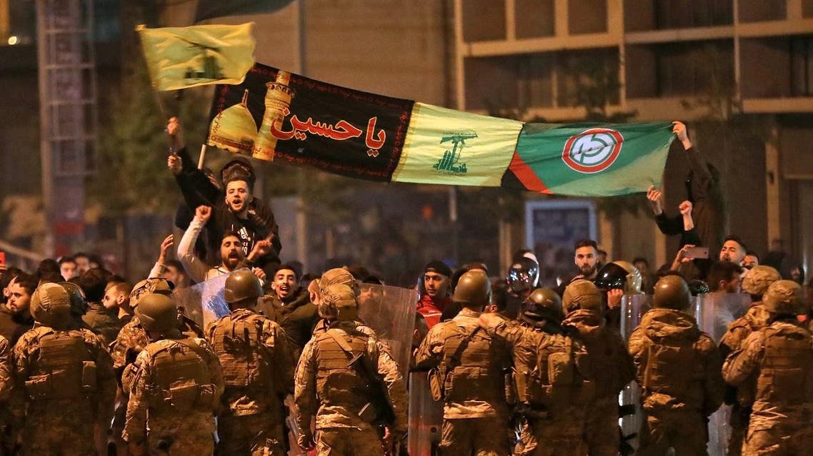 Supporters of Lebanese Shia groups Hezbollah and Amal wave flags and chant in front of army soldiers in the capital Beirut, on November 25, 2019. (AFP)
