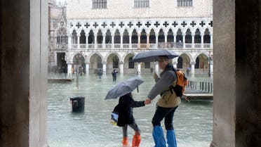 People walk in a flooded St. Mark's Square during a period of seasonal high water in Venice, Italy November 24, 2019. REUTERS