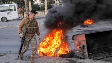 A Lebanese army soldier walks past flaming tires next to a dumpster set by anti-government protesters to block roads in the southern city of Sidon on November 19, 2019, ahead of the Lebanese parliament convening for a session in the capital Beirut. Mahmoud ZAYYAT / AFP