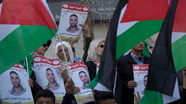 Protesters fly Palestinian flags and carry posters with pictures of Palestinian prisoner in Israeli jail, Sami Abu Diak, who died this morning, during a protest in the West Bank city of Ramallah, Tuesday, Nov. 26. 2019 (AP)