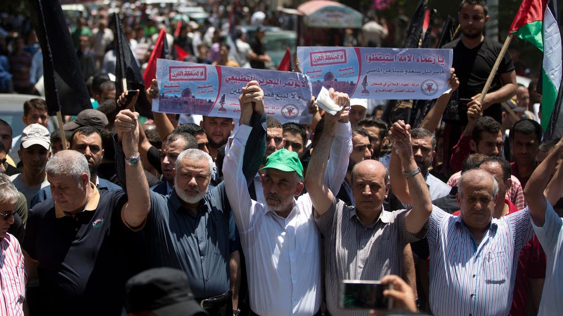 Head of the Hamas political bureau, Ismail Haniyeh, third from left, and Hamas leader in the Gaza Strip Yahya Sinwar raise their hands up with leaders of the other Palestinian factions as they attend a protest against the conference in Bahrain, which focuses on the economic portion of the White House's long-awaited plan for Mideast peace, in Gaza City, Wednesday, June 26, 2019. (AP Photo/Khalil Hamra) 