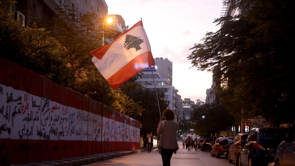 A Lebanese anti-government protester walks with her national flag during a demonstration outside the headquarters of Lebanon’s Central Bank in the capital Beirut on November 28, 2019. (AFP)