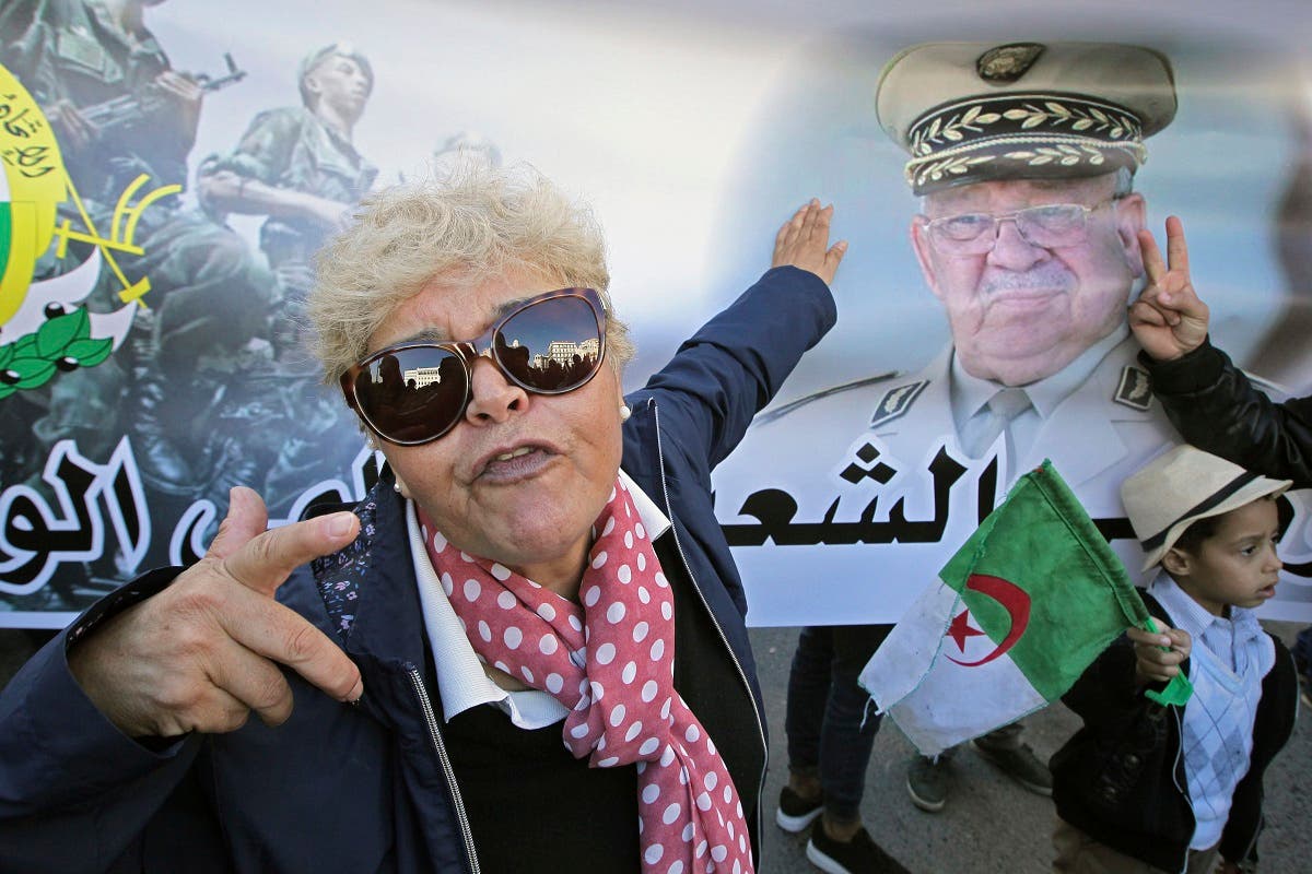 An Algerian woman gestures by a poster showing Algeria's army chief Gen.Ahmed Gaid Salah during a march against EU interference into Algeria's policy. (AP)