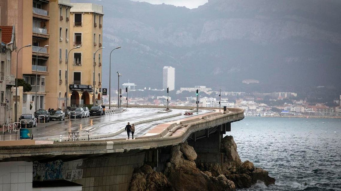 A couple walk along the coast as clouds form over Marseille, France, Sunday, Dec. 1, 2019. The southern France region is under alert for heavy rain and floods. (AP Photo/Daniel Cole)