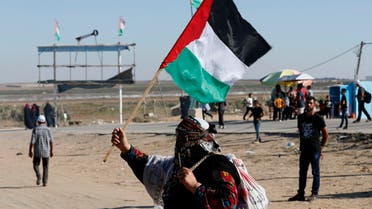 In this Sept. 25, 2019 photo, a Palestinian woman waves a national flag during a alternative protest organized by activist Ahmed Abu Artima near the separation fence between the Gaza Strip and Israel, east of Gaza City. (AP)