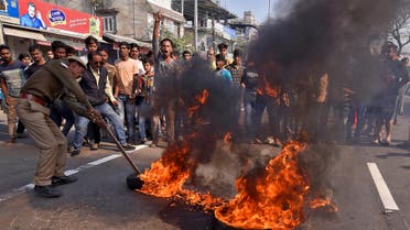 A policeman removes burning tires set ablaze by demonstrators during the strike to protest against Citizenship Amendment Bill (CAB), a bill that seeks to give citizenship to religious minorities persecuted in neighbouring Muslim countries, in Guwahati, India, December 10, 2019. (Reuters)