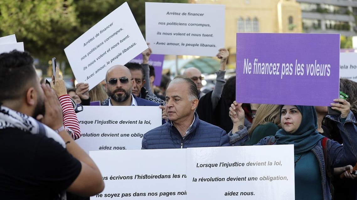 Lebanese anti-government demonstrators hold placards outside the French embassy in the capital Beirut on December 11, 2019 to protest against ISG meeting in Paris. (AFP)