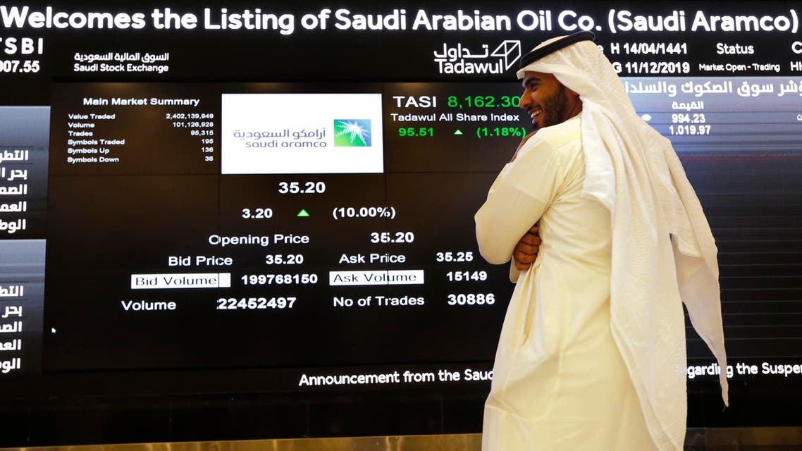 A Saudi stock market official smiles as he watches the stock market screen displaying Saudi Arabia's state-owned oil company Aramco after the debut of Aramco's initial public offering (IPO) on the Riyadh's stock market in Riyadh, Saudi Arabia, Wednesday, Dec. 11, 2019. (AP Photo/Amr Nabil)
