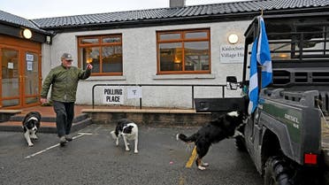 A Scottish Saltire flag hangs from a vehicle as man and his dogs leave Kinlochard Village Hall, serving as a polling station, in Kinlochard, Scotland. (AFP)