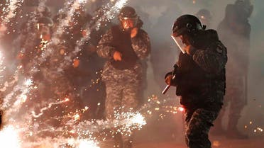 Lebanese riot policemen run from firecrackers that fired by the supporters of the Shiite Hezbollah and Amal Movement groups, as they try to attack the anti-government protesters squares, in downtown Beirut, on December 14, 2019. (AP)