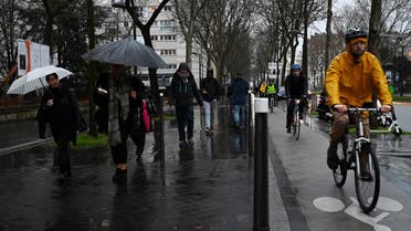 People ride bicycles and walk in the rain in Porte de Vanves in Paris, on December 16, 2019, during a strike of Paris' public transports operator RATP and of the French state railway company. (AFP)