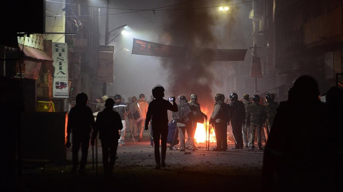 Firefighters and police personnel stand next to burning objects set on fire during demonstrations against India's new citizenship law in Kanpur on December 21, 2019. (AFP)