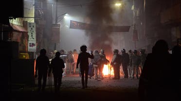Firefighters and police personnel stand next to burning objects set on fire during demonstrations against India's new citizenship law in Kanpur on December 21, 2019. (AFP)