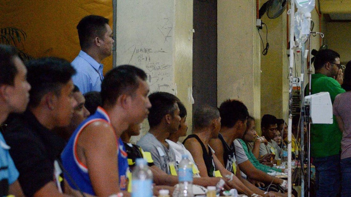 Residents who fell ill after drinking a coconut wine called "lambanog" sit as they wait for treatment at the Philippine General Hospital (PGH) in Manila. (Photo: Manila)