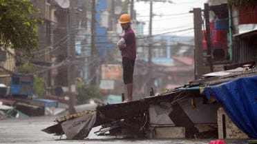 A resident stands on top of the roof of his submerged house as heavy rains brought about by Tropical Storm Fung-Wong flooded homes in Manila on September 19, 2014. Heavy rains brought y the outer bands of Tropical Storm Fung-Wong shut down the Philippine capital Manila on September 19, stranding motorists and forcing tens of thousands to flee their flooded homes, officials said. (AFP)