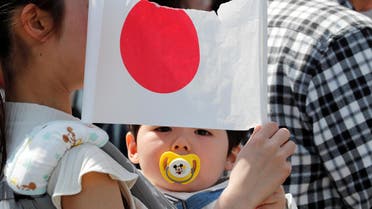 A baby holds a Japanese national flag outside the Imperial Palace before the first public appearance of Japan's Emperor Naruhito and Empress Masako in Tokyo, Japan May 4, 2019. REUTERS/Kim Kyung-Hoon