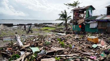 Residents walk past a house damaged during Typhoon Phanfone in Tacloban, Leyte province in the central Philippines on December 25, 2019. Typhoon Phanfone pummelled the central Philippines on Christmas Day, bringing a wet and miserable holiday season to millions in the mainly Catholic nation.