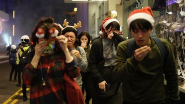 Residents dressed for Christmas festivities react to tear gas as police confront protesters on Christmas Eve in Hong Kong on December 24, 2019. (AP) 