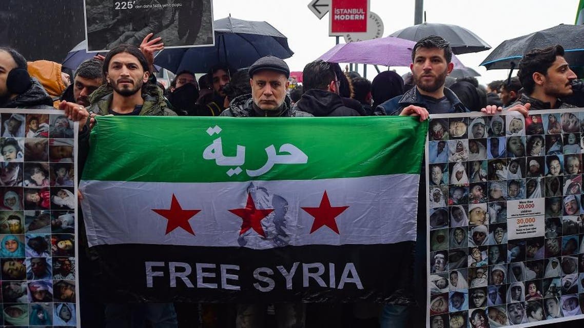 Protestors hold a Syrian flag and placards reading "More than 30.000 children killed by Russia and Assad regime" and bearing photographs of the victims. (AFP)