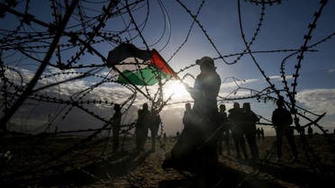 Palestinian protesters wave a national flag near concertina wire at the Israel-Gaza border. (AFP)
