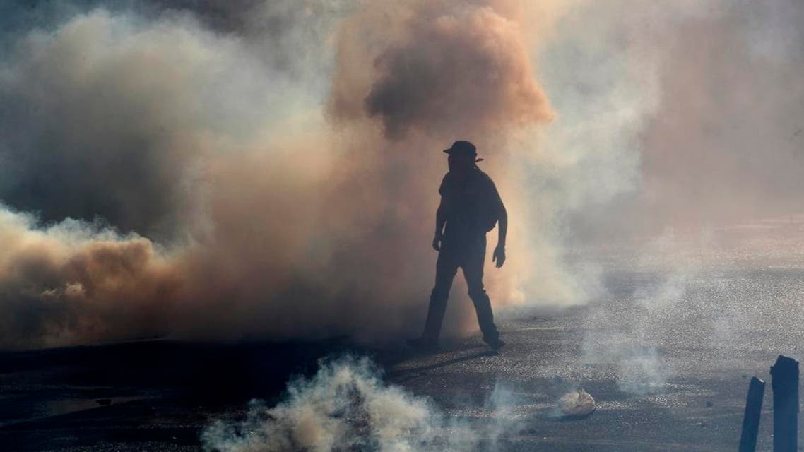 A protester stands amid tear gas fired by police trying to disperse an anti-government demonstration in Santiago, Chile. (AP)