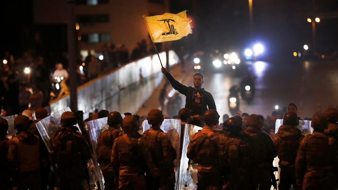 A supporter of the Iran-backed militant Hezbollah group waves his group's flag as he stands in front of Lebanese army soldiers after a clash erupted between the anti-government protesters and the group, in Beirut, Lebanon, early Monday, Nov. 25, 2019. (AP)