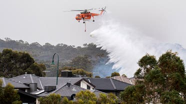 A skycrane drops water on a bushfire in scrub behind houses in Bundoora, Melbourne, Monday, Dec. 30, 2019. (AP)