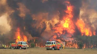 In this image dated Dec. 30, 2019, and provided by NSW Rural Fire Service via their twitter account, firefighters are seen as they try to protect homes around Charmhaven, New South Wales. Wildfires burning across Australia's two most-populous states Tuesday trapped residents of a seaside town in apocalyptic conditions, destroyed many properties and caused fatalities. (Twitter@NSWRFS via AP)