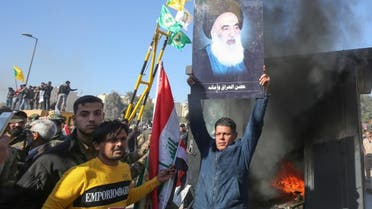 An Iraqi supporter of the PMF lifts a picture of Iraq’s top Shia cleric Grand Ayatollah Ali Sistani. (AFP)