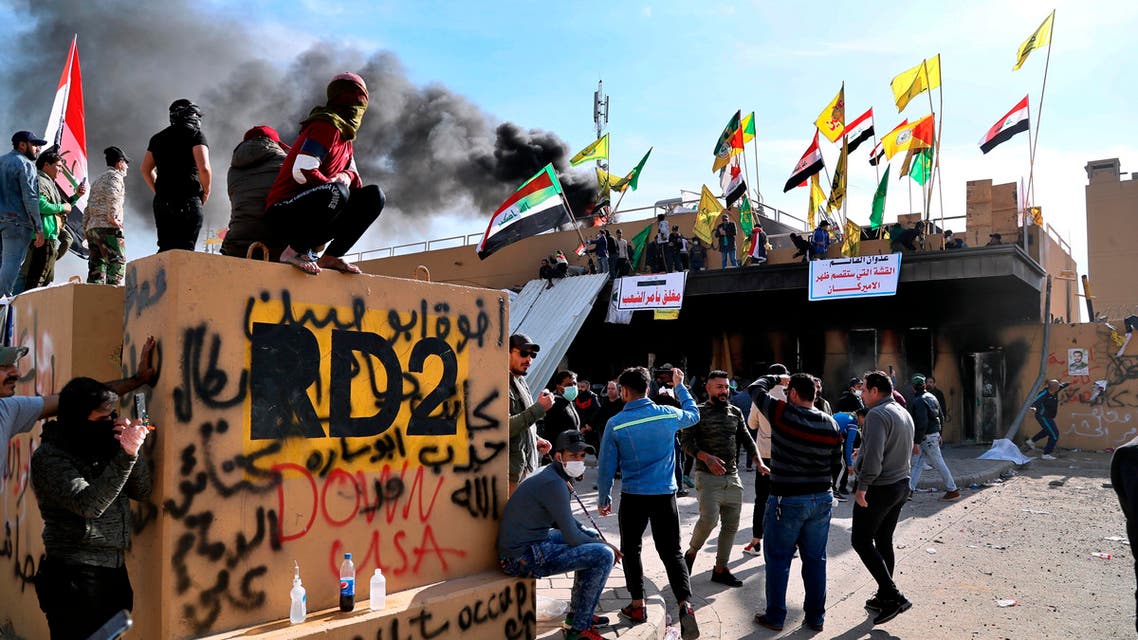 Pro-Iranian militiamen set a fire during a sit-in in front of the US embassy in Baghdad on Jan. 1, 2020. (AP)
