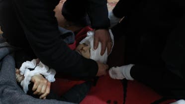 Medics wrap the body of a boy, who was killed following a missile fired by Syrian regime forces. (AFP)