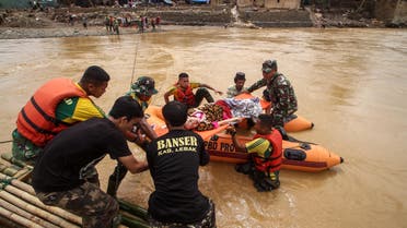 Rescuers help a sick woman cross the river to get medical assistance at the Sukarame village in Lebak. (AFP)