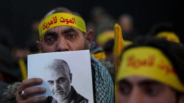 A supporter of Hezbollah leader Sayyed Hassan Nasrallah holds a portrait of slain Iranian Revolutionary Guard Gen. Qassem Soleimani before a televised speech by Nasrallah in a southern suburb of Beirut, Lebanon, Sunday, Jan. 5, 2020 following the U.S. airstrike in Iraq that killed Soleimani. His headband reads: "death to America." (AP Photo