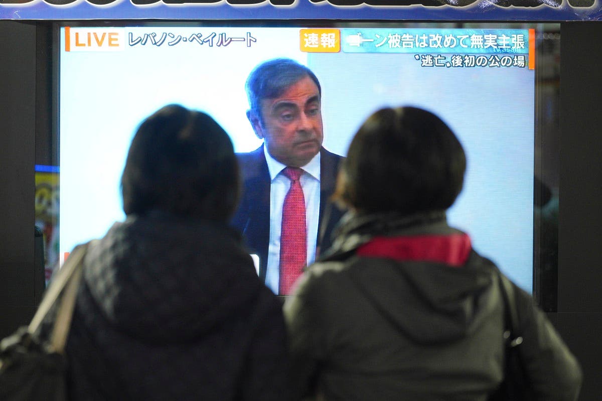People in Tokyo watch a public TV showing a live broadcast of former Nissan chairman Carlos Ghosn speaking from Lebanon at his press conference Wednesday, Jan. 8, 2020. (AP)