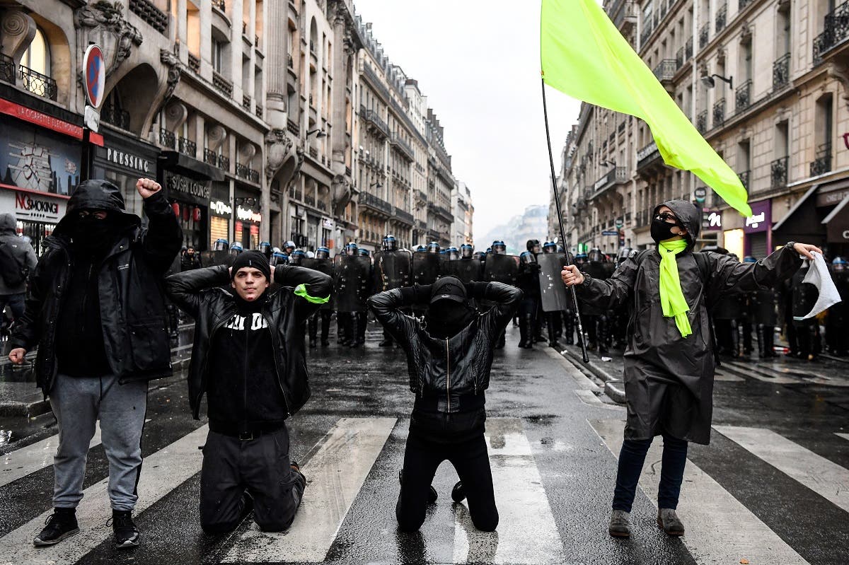 Protesters kneel and gestures in front of a police cordon during a demonstration in Paris, on January 9, 2020, on the 36th day of a nationwide multi-sector strike against French government's pensions overhaul. (AFP)