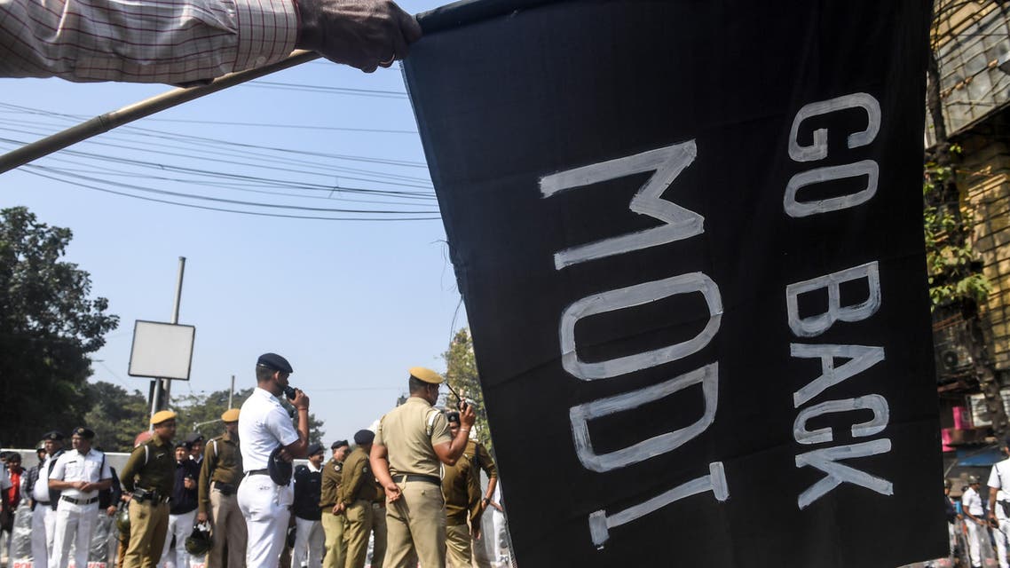 A demonstrator holds a flag on which is written 'Go Back Modi' to protest against Indian Prime Minister Narendra Modi as police personnel stands guard, during a demonstration in Kolkata on January 12, 2020. (AFP)