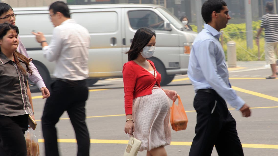 This photo taken on June 20, 2013 shows a pregnant woman with a face mask walking on the street in Singapore. Singapore's smog index hit the critical 400 level on June 21, making it potentially life-threatening to the ill and elderly people, according to a government monitoring site. AFP PHOTO/Roslan Rahman