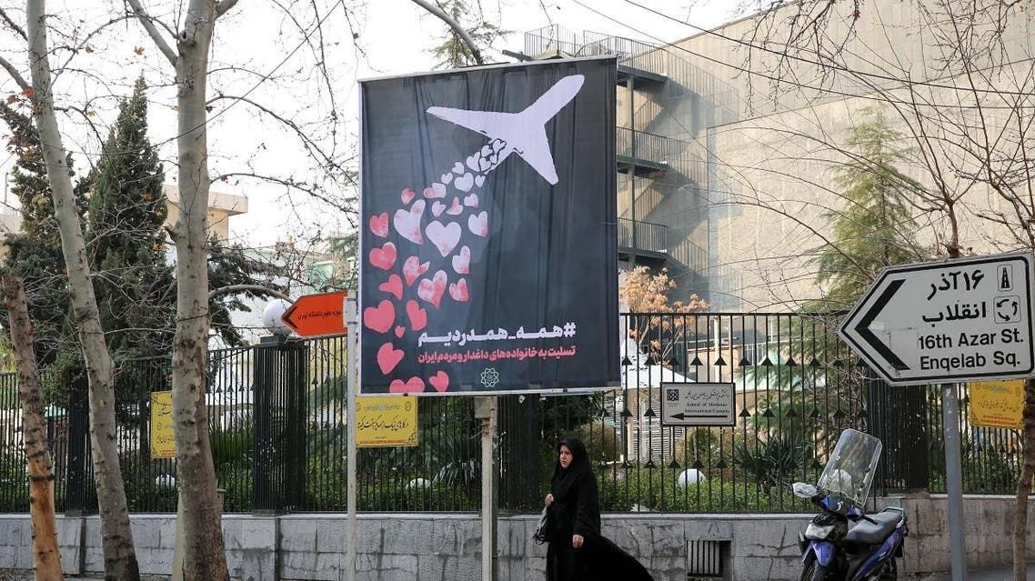 An Iranian woman walks beneath a poster honouring the victims of a Ukrainian passenger jet accidentally shot down in the capital last week, in front of the Amirkabir University in the capital Tehran, on January 13, 2020. (AFP)
