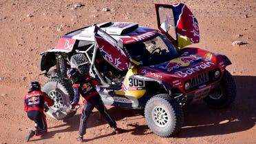 Mini's Spanish drivers Carlos Sainz of Spain and co-driver Lucas Cruz of Spain repairs their car after a flat tire during the 2020 Rally Dakar Stage 9 of the Dakar 2020 between Wadi Al Dawasir and Haradh, Saudi Arabia. (Reuters)