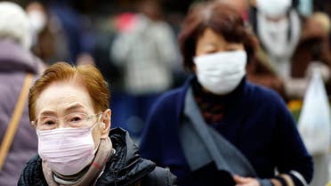 Pedestrians wear protective masks as they walk through a shopping district in Tokyo on January 16, 2020. (AP)