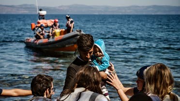 A migrant with a child is helped by rescuers as he arrives on the Greek island of Lesbos after crossing the Aegean Sea from Turkey, on September 16, 2019. Migration is a hot political issue in Europe, which experienced a wave of more than a million asylum-seekers in 2015, most of them from war-ravaged Syria.
