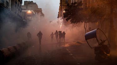 Anti-government protesters walk through clouds of tear gas during clashes with security forces in the central downtown district of the Lebanese capital near the parliament headquarters on January 18, 2020. (AFP)
