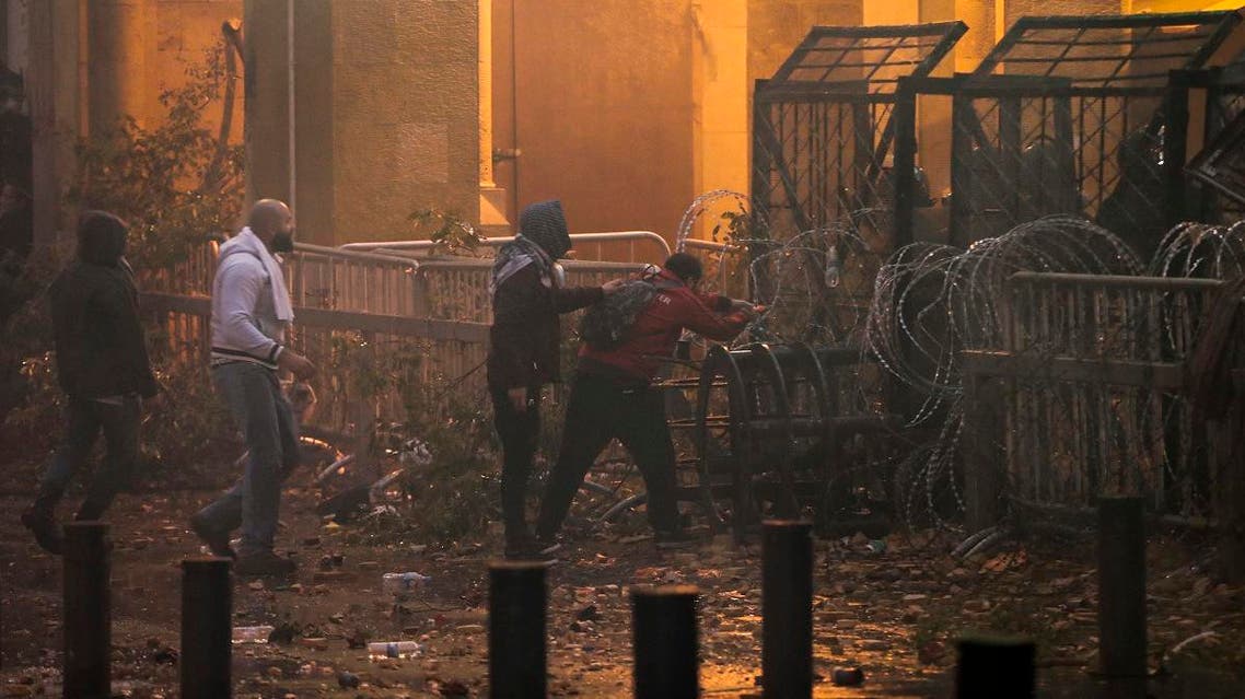 Anti-government protesters attempt to break through the security barrier in the central downtown district of the Lebanese capital Beirut near the parliament headquarters during clashes with security forces on January 18, 2020. (AFP)