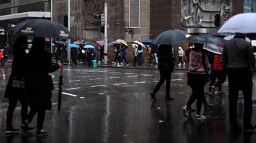 Office employees brace the rain during their lunch time break in the central business district of Sydney on September 17, 2019. (AFP)